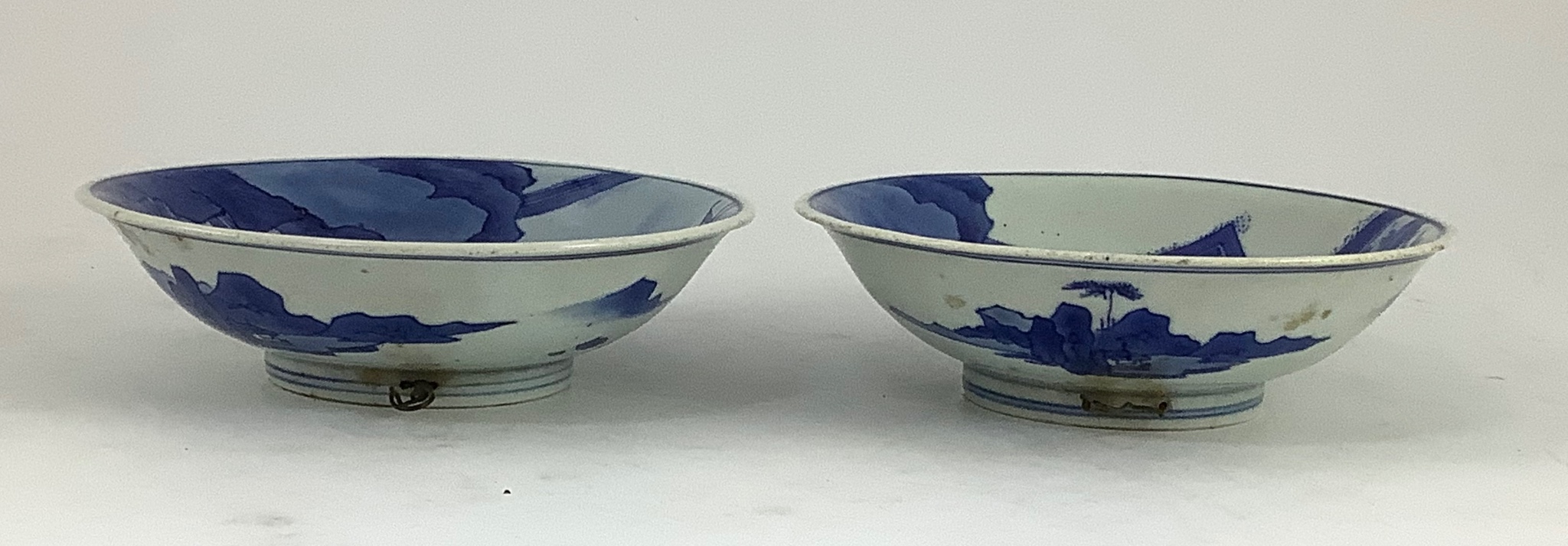 NB BOTH WITH HAIRLINE CRACKS A pair of Chinese blue and white small dishes, Kangxi six character marks and of the period (1662-1722), 15.7cm and 15.8cm diameter, foot later pierced, hairline cracks